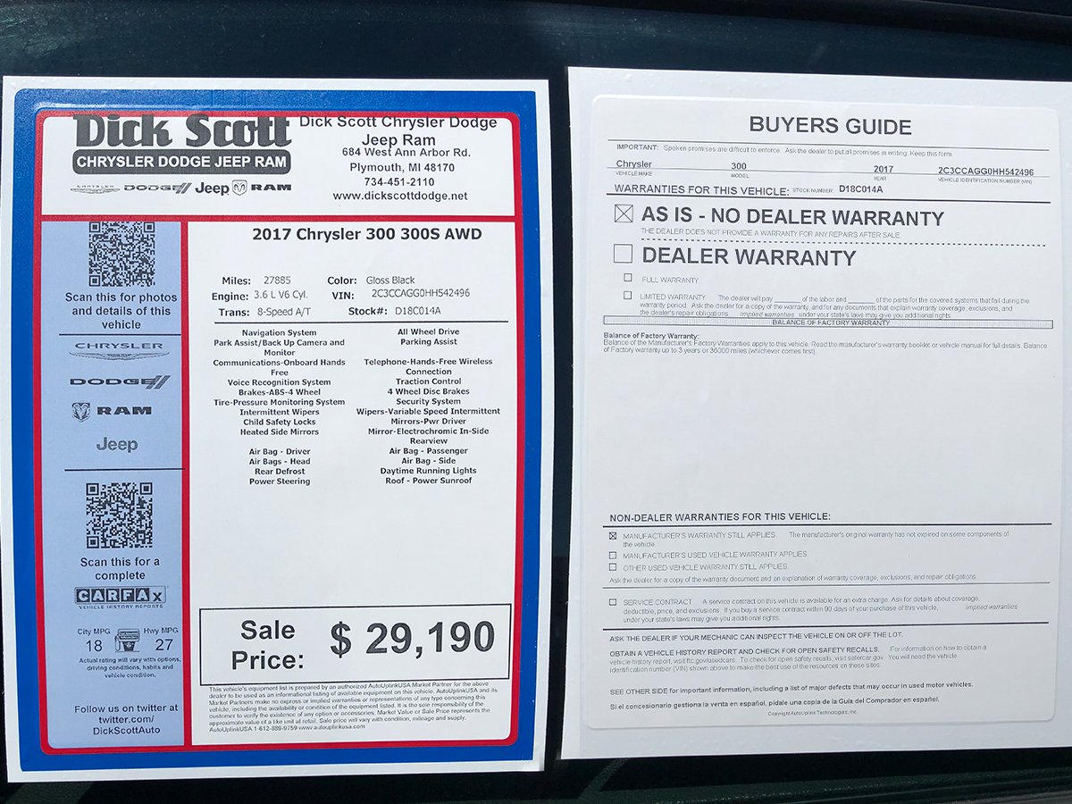 Photo of a red, white and blue window sticker and AS IS Buyer's Guide
